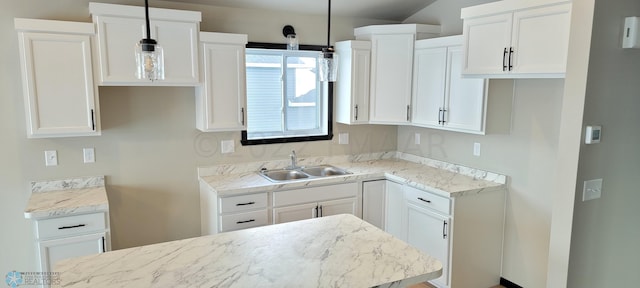kitchen featuring decorative light fixtures, light stone counters, white cabinets, and a sink