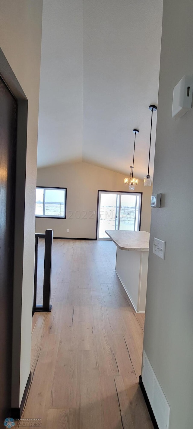 corridor with visible vents, a chandelier, light wood-style flooring, and lofted ceiling