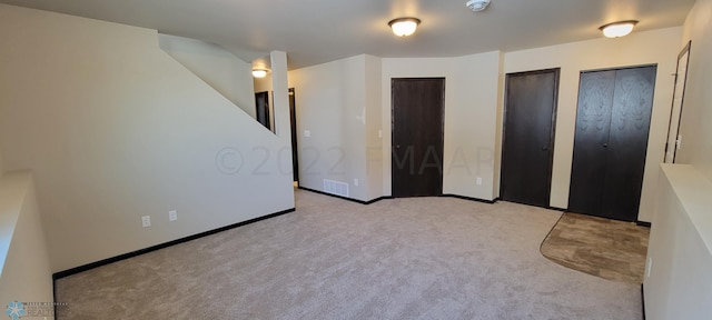 unfurnished bedroom with carpet flooring, multiple closets, and visible vents