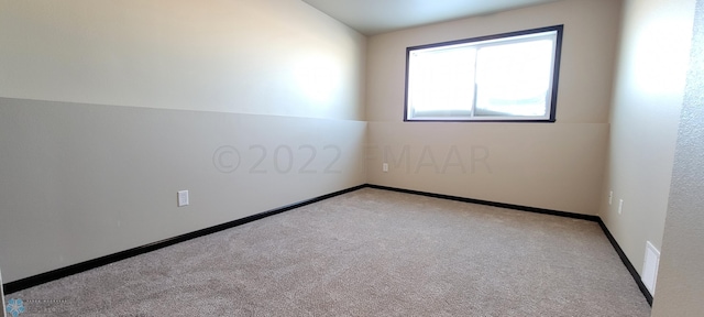 carpeted empty room featuring baseboards