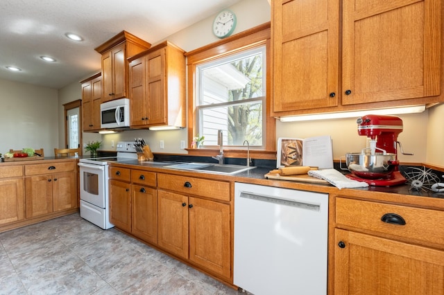 kitchen featuring white appliances, a sink, recessed lighting, and brown cabinets