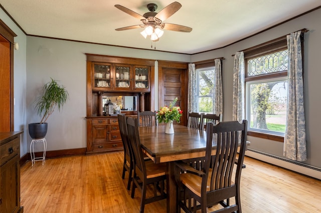 dining space featuring crown molding, light wood-type flooring, ceiling fan, baseboards, and a baseboard radiator