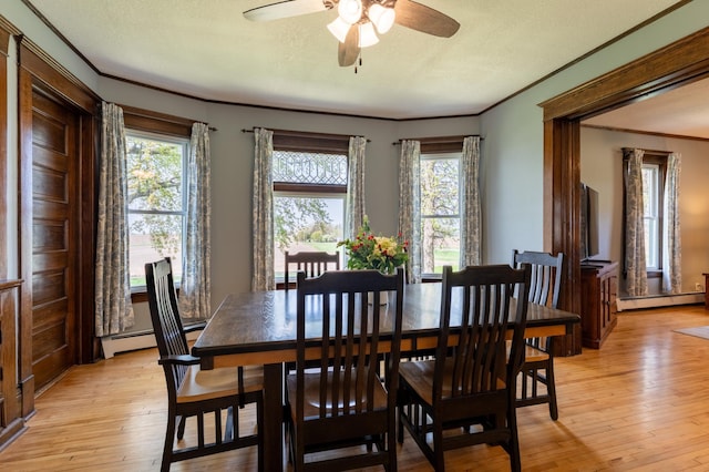 dining room with baseboard heating, crown molding, a ceiling fan, light wood-style floors, and a textured ceiling