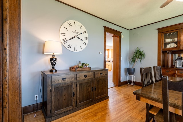 dining room featuring crown molding, light wood-type flooring, ceiling fan, and baseboards