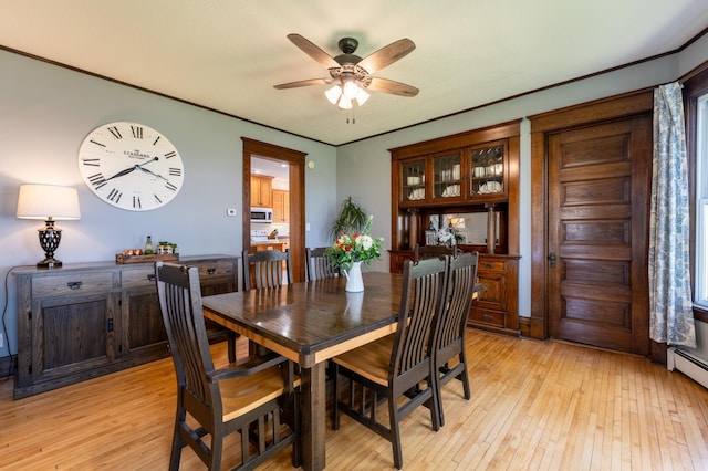 dining area featuring a ceiling fan, light wood-style flooring, baseboard heating, and crown molding