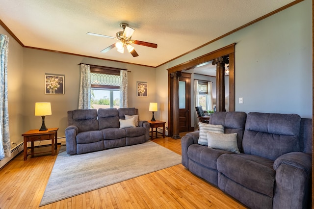living area featuring ceiling fan, ornamental molding, light wood finished floors, and a textured ceiling