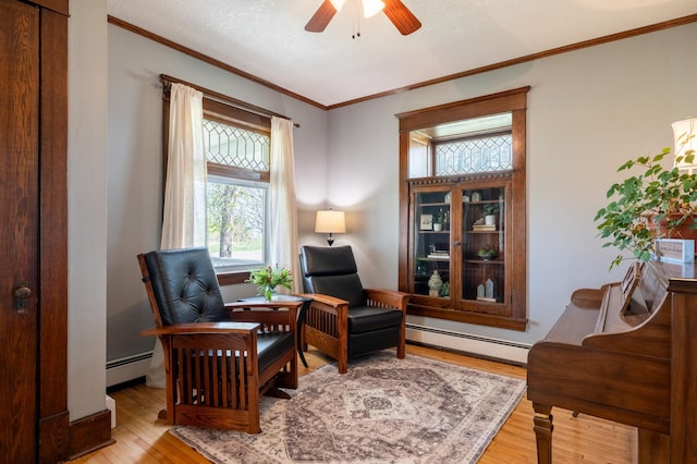 sitting room featuring a baseboard radiator, light wood-style floors, ceiling fan, ornamental molding, and a desk