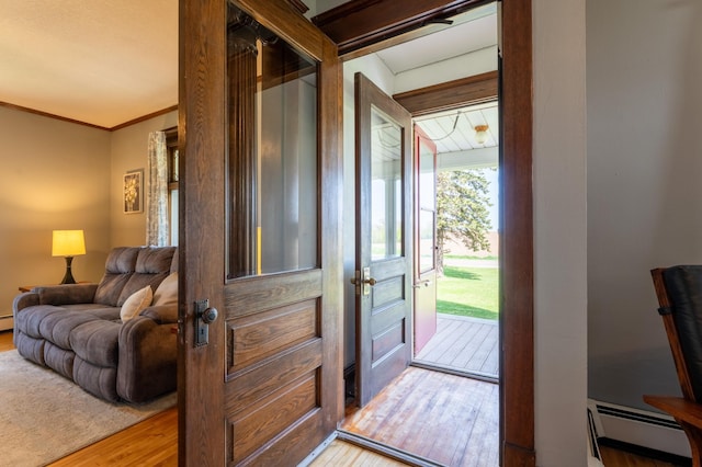 entrance foyer featuring a baseboard radiator, wood finished floors, and crown molding