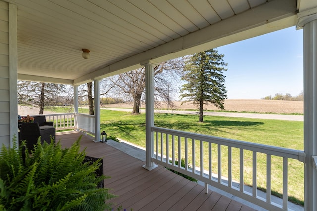 deck with covered porch, a lawn, and a view of countryside
