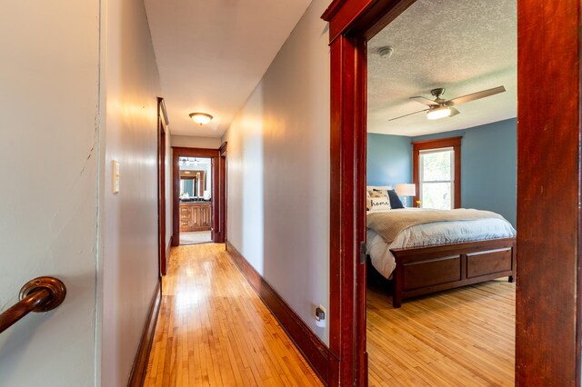 corridor with light wood-type flooring and baseboards
