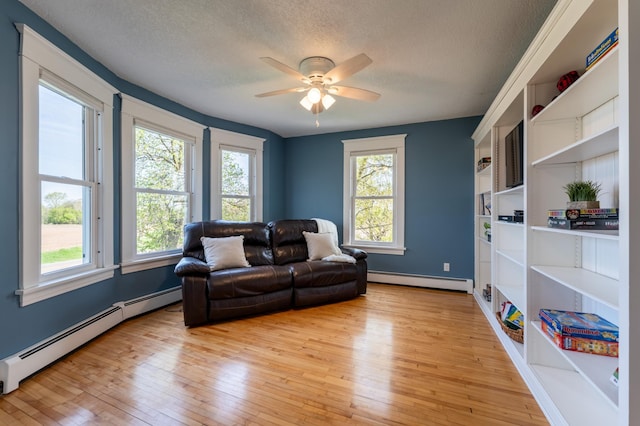 living room featuring a baseboard radiator, a textured ceiling, light wood-style floors, ceiling fan, and baseboards
