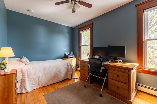 bedroom with baseboard heating, multiple windows, and a desk