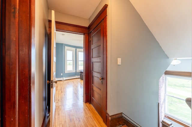 corridor featuring baseboard heating, light wood finished floors, and baseboards