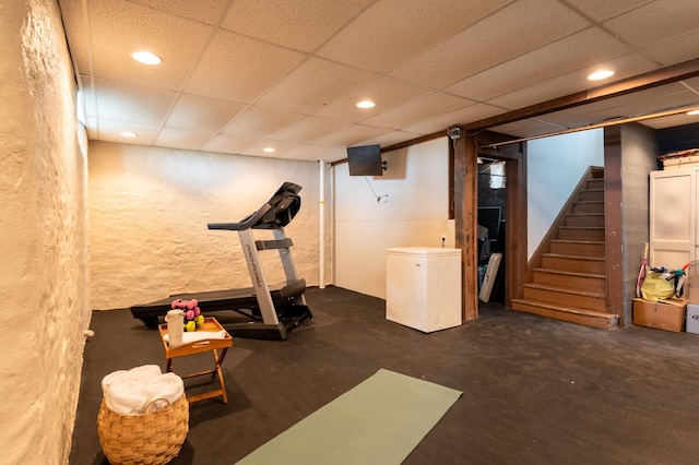 workout room featuring a paneled ceiling, recessed lighting, and a textured wall