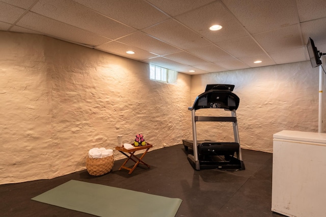 workout area featuring a drop ceiling, a textured wall, and recessed lighting