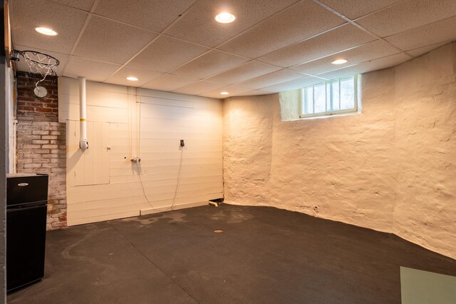 basement with a drop ceiling, recessed lighting, and a textured wall