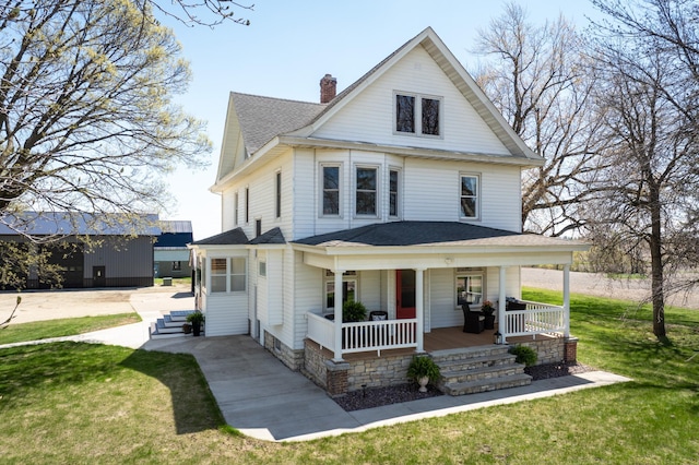 traditional style home featuring a chimney, a porch, a front lawn, and a shingled roof