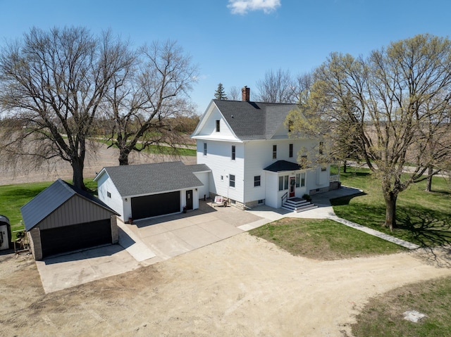 view of home's exterior with a chimney, a shingled roof, concrete driveway, an outdoor structure, and a yard