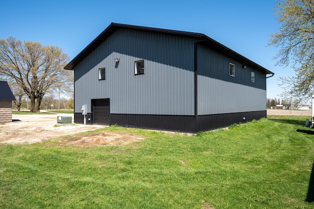 view of property exterior with a lawn, a garage, and central AC