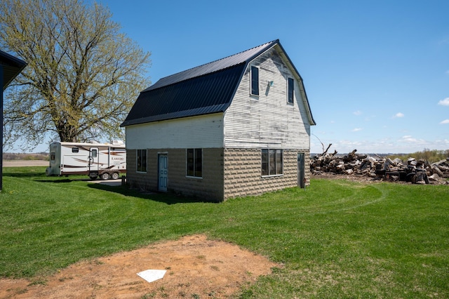 view of property exterior featuring a gambrel roof, metal roof, a yard, and a barn
