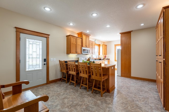 kitchen with a peninsula, baseboards, plenty of natural light, a textured ceiling, and recessed lighting