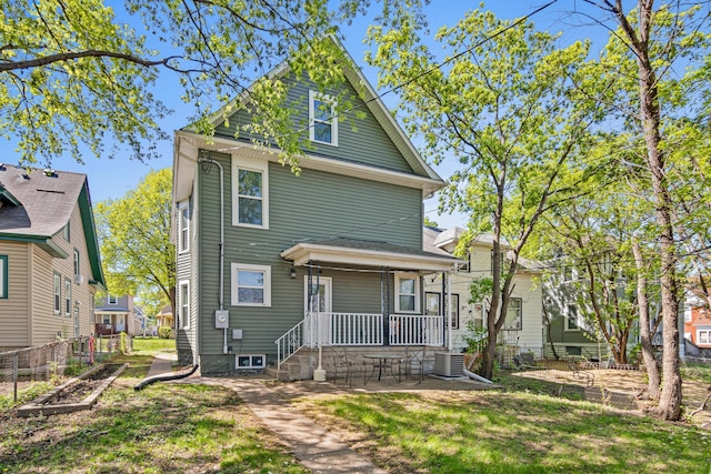 american foursquare style home featuring covered porch, a front yard, and central AC