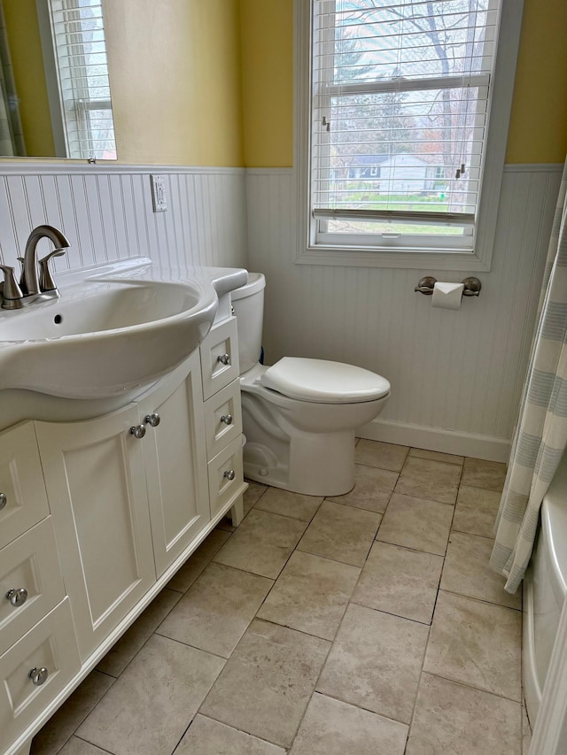 bathroom featuring vanity, tile patterned floors, toilet, wainscoting, and a shower with shower curtain