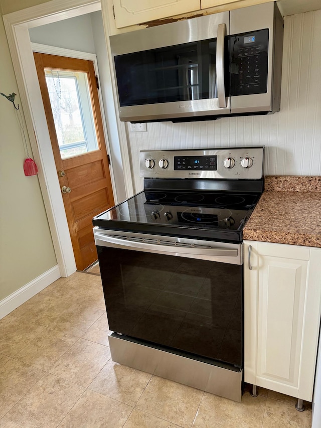 kitchen featuring light tile patterned floors, stainless steel appliances, and baseboards