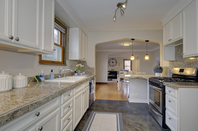 kitchen featuring appliances with stainless steel finishes, a sink, white cabinetry, arched walkways, and tasteful backsplash