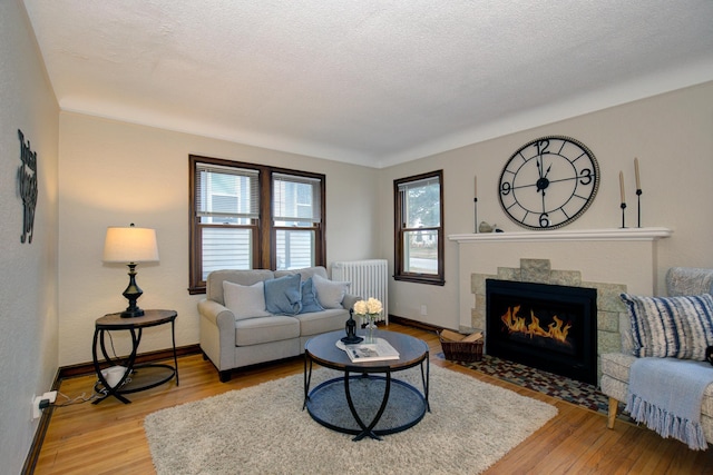 living room with radiator, light wood finished floors, baseboards, and a fireplace