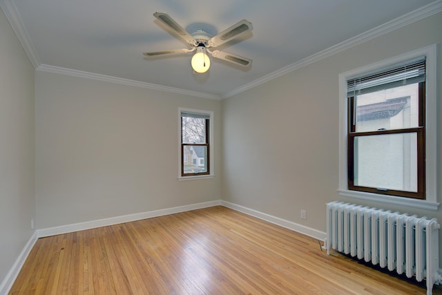 spare room featuring radiator, light wood-type flooring, crown molding, baseboards, and ceiling fan