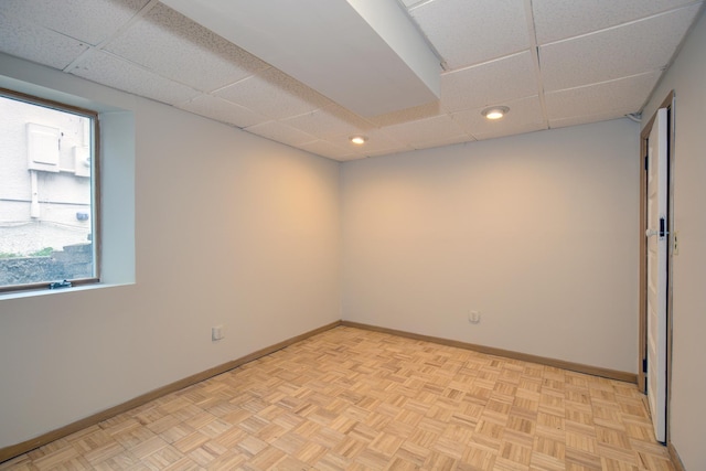 spare room featuring a drop ceiling, recessed lighting, and baseboards