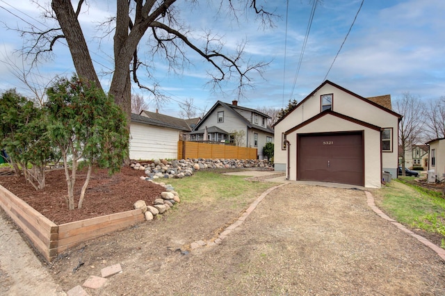 view of front facade featuring driveway, stucco siding, and fence