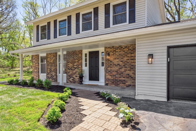 view of front facade featuring brick siding, covered porch, and a garage