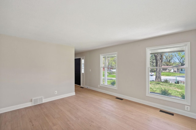 unfurnished room with light wood-style floors, baseboards, and healthy amount of natural light
