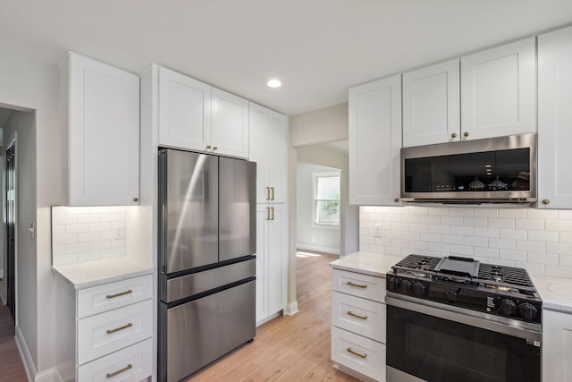kitchen with stainless steel appliances, light wood-style flooring, light stone counters, and recessed lighting