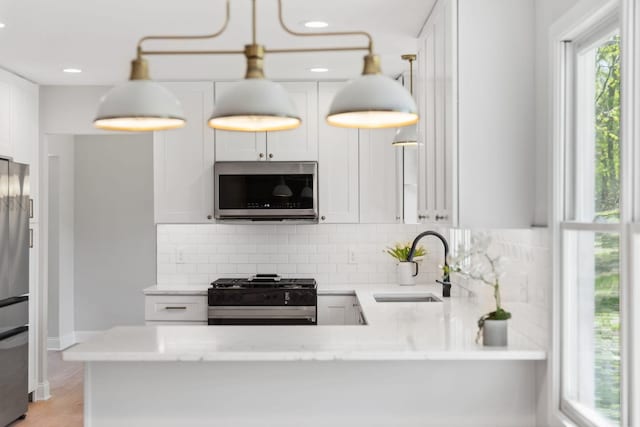kitchen featuring stainless steel appliances, a sink, decorative backsplash, light stone countertops, and recessed lighting
