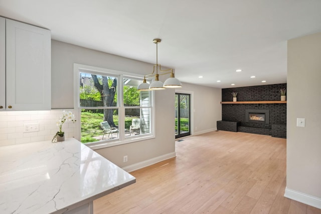 dining room with baseboards, a fireplace, recessed lighting, and light wood finished floors