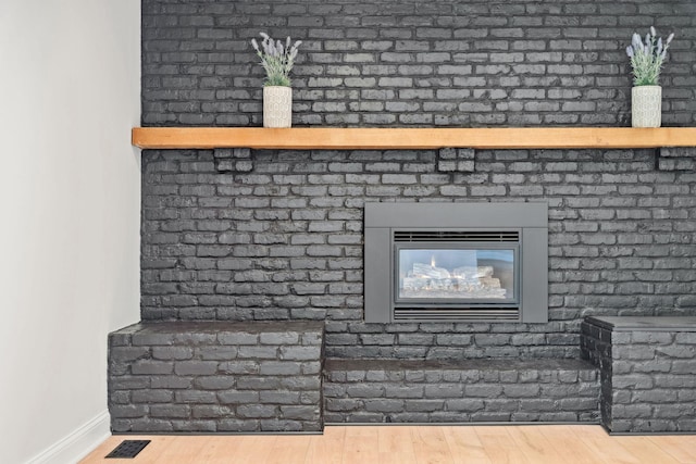 detailed view of baseboards, wood finished floors, and a fireplace
