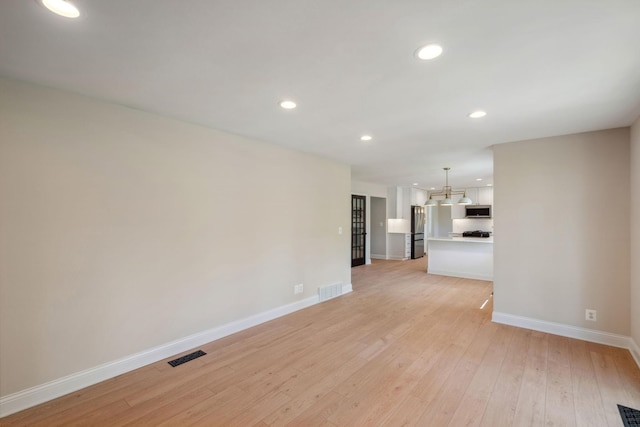 unfurnished living room with baseboards, light wood-type flooring, recessed lighting, and a chandelier