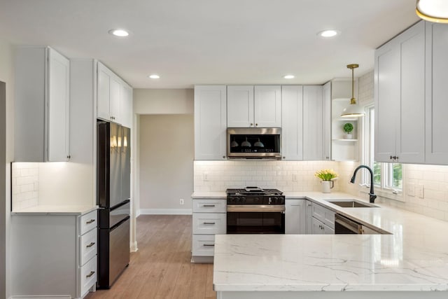 kitchen with stainless steel appliances, a sink, a peninsula, open shelves, and recessed lighting