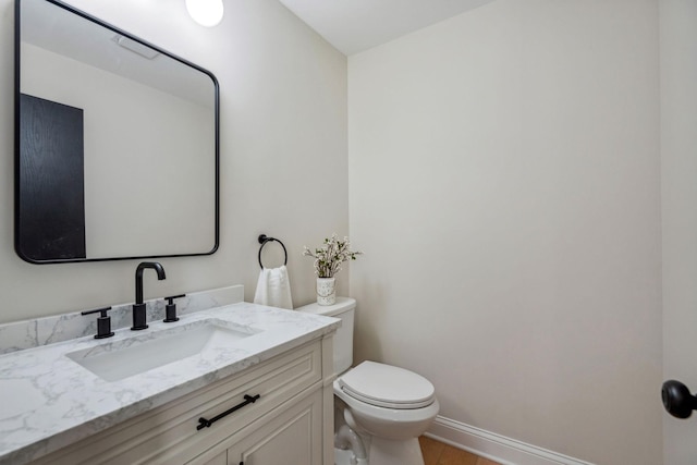 half bath with toilet, vanity, and baseboards