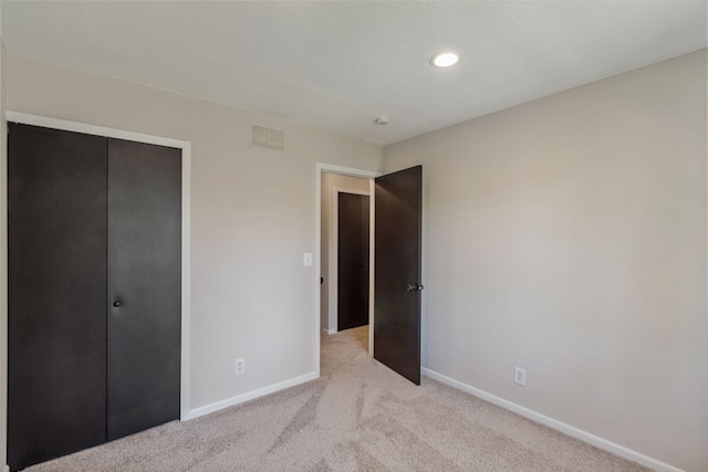 unfurnished bedroom with baseboards, light carpet, a closet, and recessed lighting