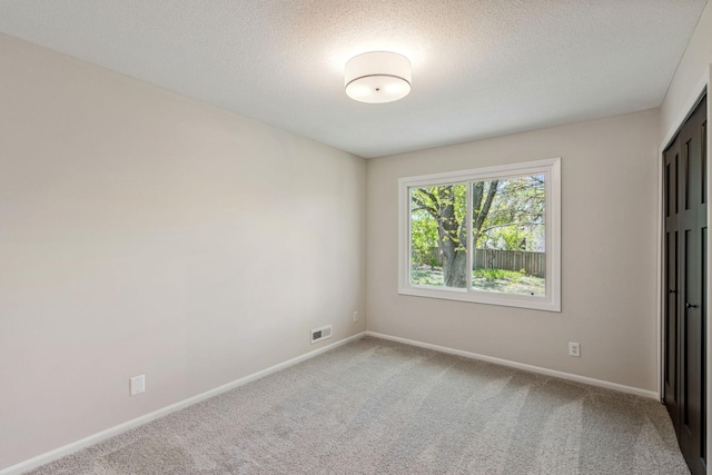 carpeted empty room with baseboards and a textured ceiling