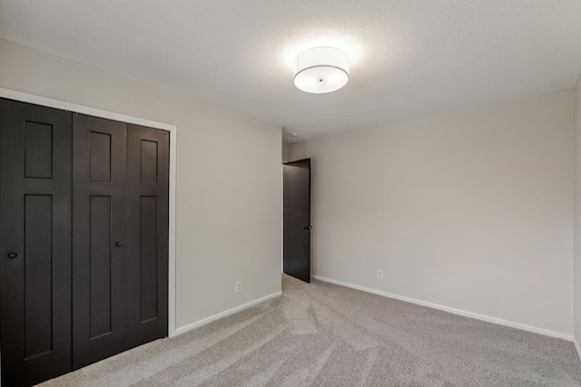 unfurnished bedroom featuring light carpet, baseboards, and a closet