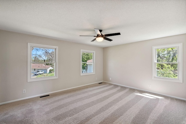 carpeted empty room with ceiling fan, baseboards, and a textured ceiling
