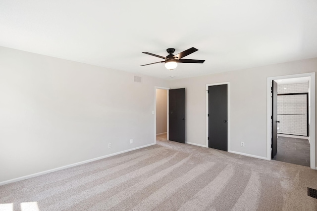 unfurnished bedroom with baseboards, light carpet, ensuite bath, and ceiling fan