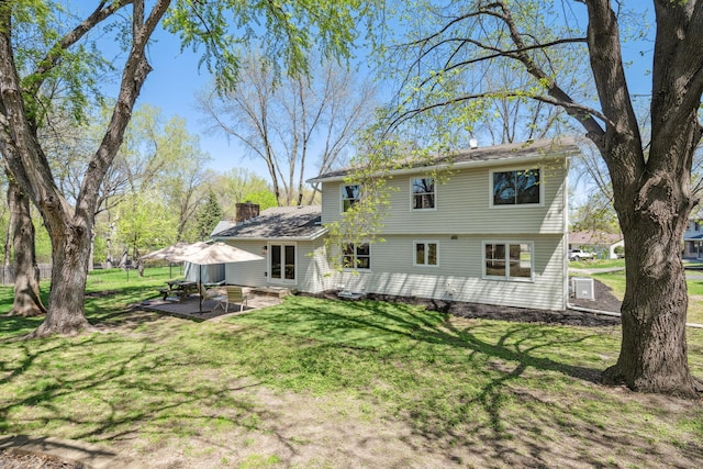 back of house with a patio, a yard, and a chimney