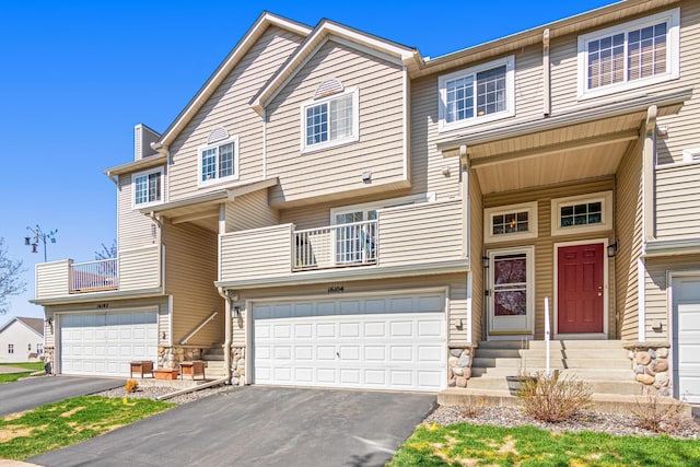 view of property featuring a garage, entry steps, driveway, and a balcony