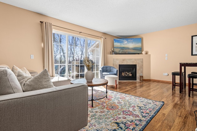 living area with a textured ceiling, a fireplace, and wood finished floors